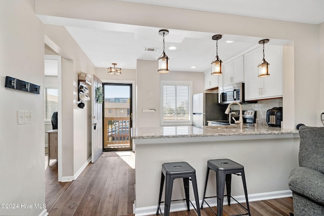 kitchen featuring white cabinets, dark hardwood / wood-style floors, kitchen peninsula, and stainless steel appliances