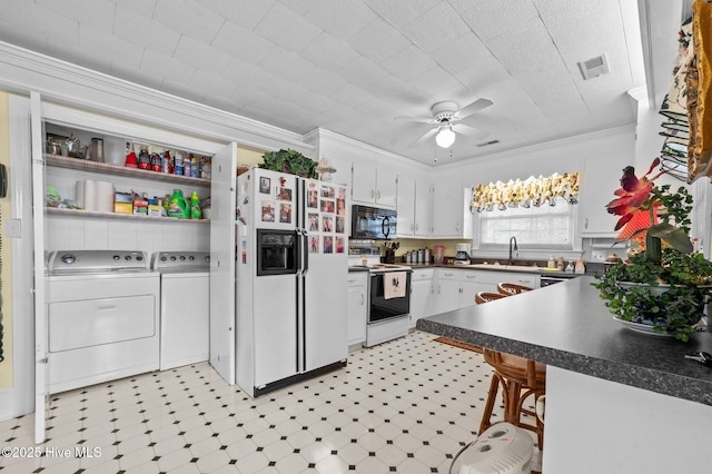 kitchen with white appliances, washer and clothes dryer, white cabinets, sink, and ornamental molding