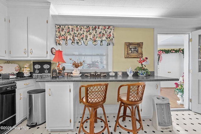 kitchen featuring kitchen peninsula, white cabinets, a breakfast bar, and crown molding