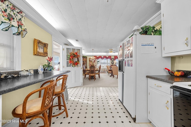 kitchen with white cabinets, a wealth of natural light, and white appliances