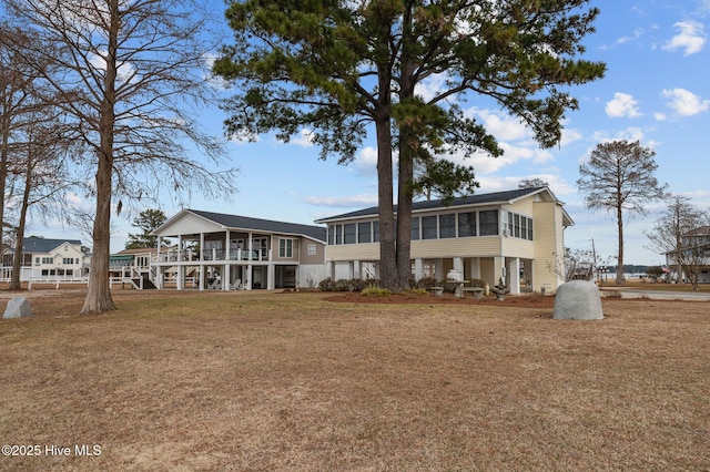 rear view of property with a sunroom and a lawn