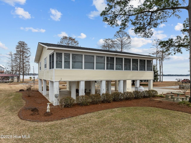 view of front of property with a front lawn, a sunroom, and a water view