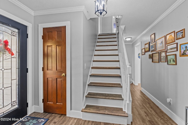 stairway with hardwood / wood-style flooring, an inviting chandelier, crown molding, and a textured ceiling