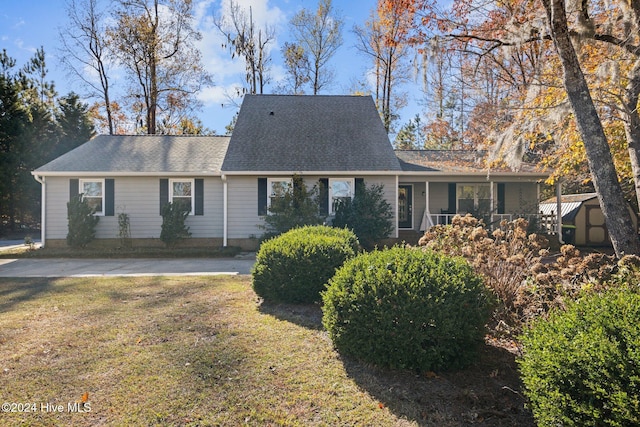 view of front of house featuring covered porch, a shed, and a front lawn