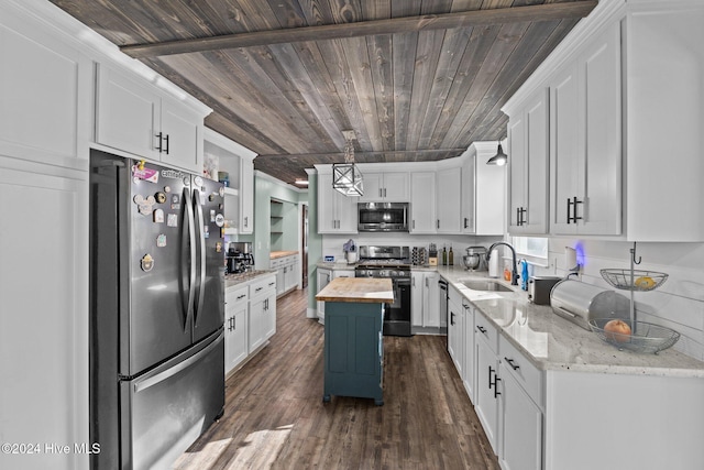 kitchen with appliances with stainless steel finishes, sink, white cabinets, a center island, and butcher block countertops