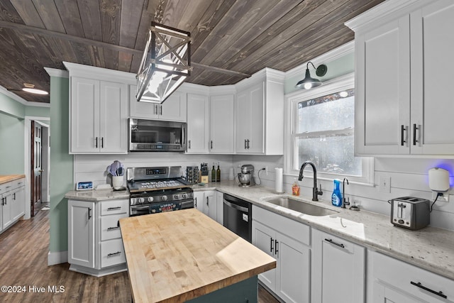 kitchen with sink, hanging light fixtures, wood counters, white cabinets, and appliances with stainless steel finishes