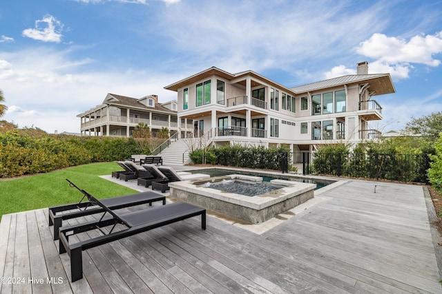 back of property featuring a lawn, a balcony, an in ground hot tub, and a wooden deck