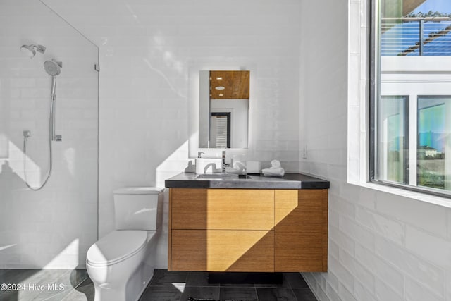 bathroom featuring tile patterned floors, vanity, toilet, and a tile shower