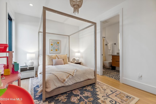 bedroom with ensuite bathroom and wood-type flooring