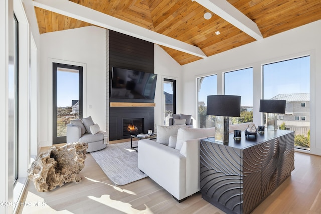 living room featuring beam ceiling, high vaulted ceiling, light hardwood / wood-style floors, a fireplace, and wood ceiling