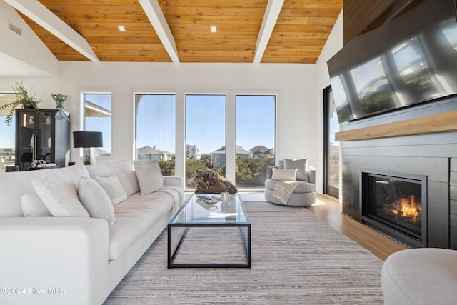 living room with lofted ceiling with beams, a large fireplace, light hardwood / wood-style flooring, and wooden ceiling