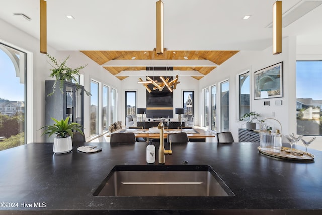 kitchen featuring beamed ceiling, a notable chandelier, wooden ceiling, and a wealth of natural light