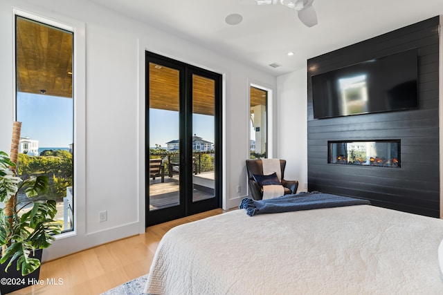 bedroom with access to exterior, ceiling fan, a fireplace, and light hardwood / wood-style flooring