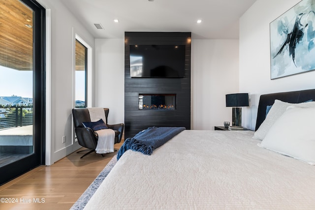 bedroom with hardwood / wood-style floors and a large fireplace