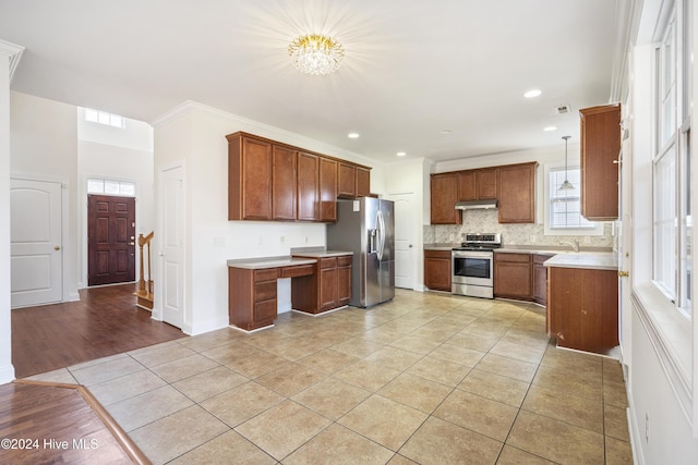 kitchen featuring stainless steel appliances, an inviting chandelier, hanging light fixtures, and ornamental molding