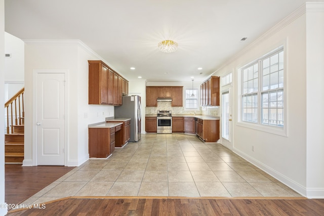 kitchen with backsplash, crown molding, appliances with stainless steel finishes, and light hardwood / wood-style flooring