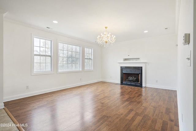 unfurnished living room with an inviting chandelier, dark wood-type flooring, and ornamental molding