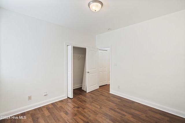 unfurnished bedroom featuring a closet and dark wood-type flooring