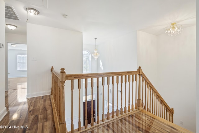 stairway featuring hardwood / wood-style flooring and a chandelier