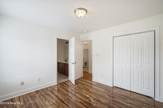 unfurnished bedroom featuring hardwood / wood-style floors, ensuite bathroom, and a closet