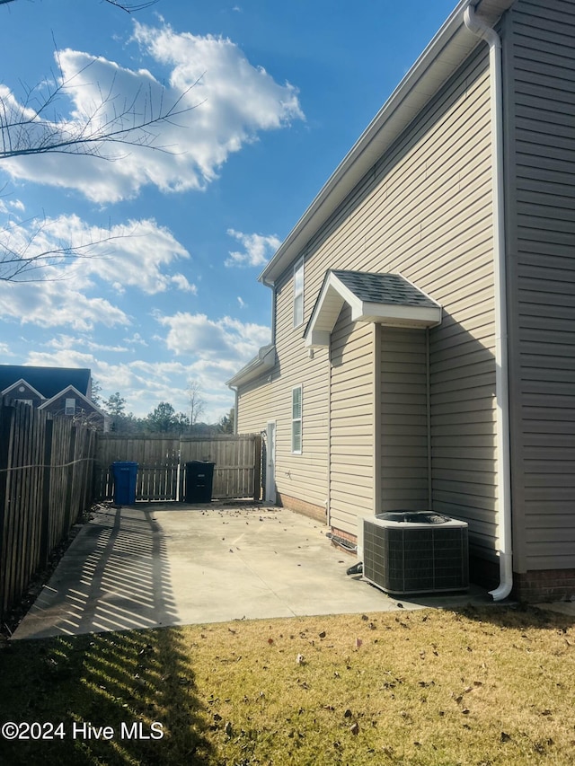 view of side of home featuring a patio, a lawn, and central air condition unit