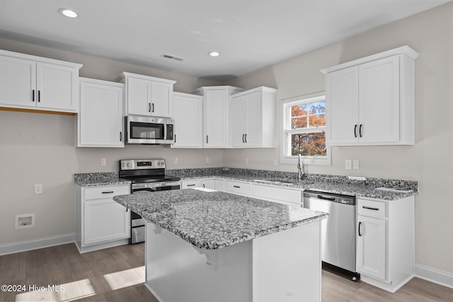 kitchen with visible vents, white cabinets, a kitchen island, appliances with stainless steel finishes, and light stone countertops