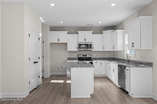 kitchen with a kitchen island, appliances with stainless steel finishes, sink, and dark stone counters