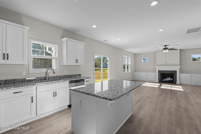 kitchen with appliances with stainless steel finishes, white cabinetry, sink, dark stone counters, and light wood-type flooring