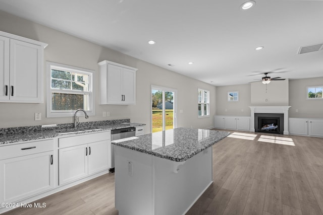 kitchen with a fireplace with flush hearth, a sink, visible vents, and light wood-style floors