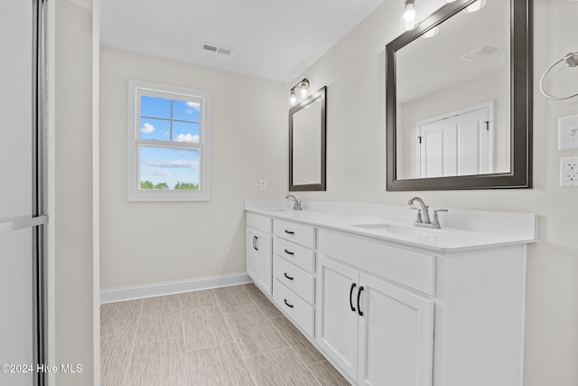 full bath featuring double vanity, a sink, visible vents, and baseboards