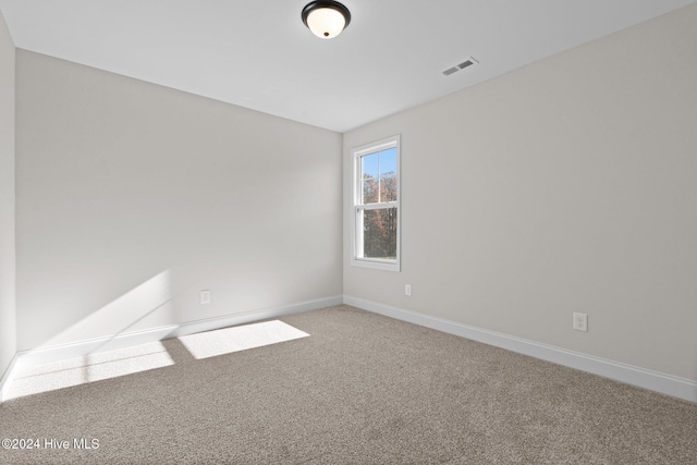 carpeted empty room featuring visible vents and baseboards