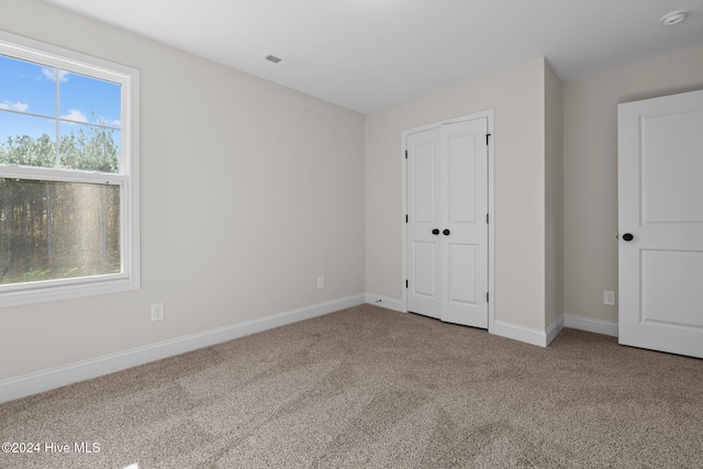 unfurnished bedroom with baseboards, multiple windows, and carpet flooring