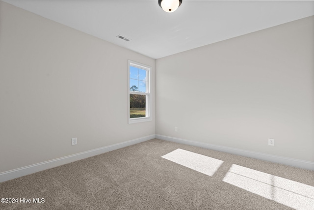 empty room featuring carpet floors, visible vents, and baseboards