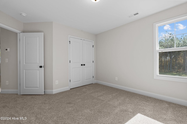 unfurnished bedroom with a closet, carpet, visible vents, and baseboards