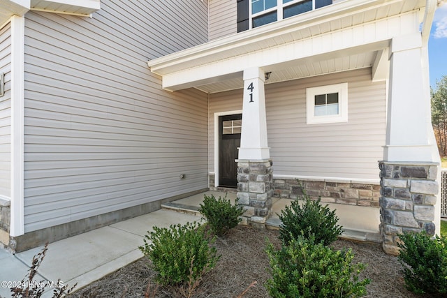 doorway to property with covered porch and stone siding