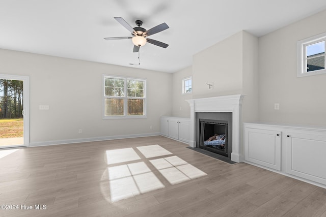 unfurnished living room with ceiling fan, a fireplace with flush hearth, light wood-style flooring, and baseboards