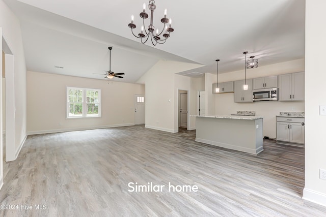 unfurnished living room featuring vaulted ceiling, ceiling fan with notable chandelier, and light wood-type flooring