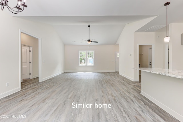 unfurnished living room featuring light hardwood / wood-style flooring, ceiling fan with notable chandelier, and vaulted ceiling