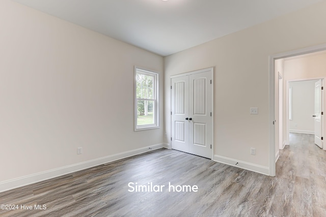 unfurnished bedroom with light wood-type flooring and a closet