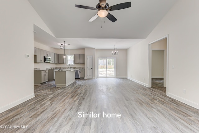 unfurnished living room with hardwood / wood-style floors, ceiling fan with notable chandelier, and vaulted ceiling