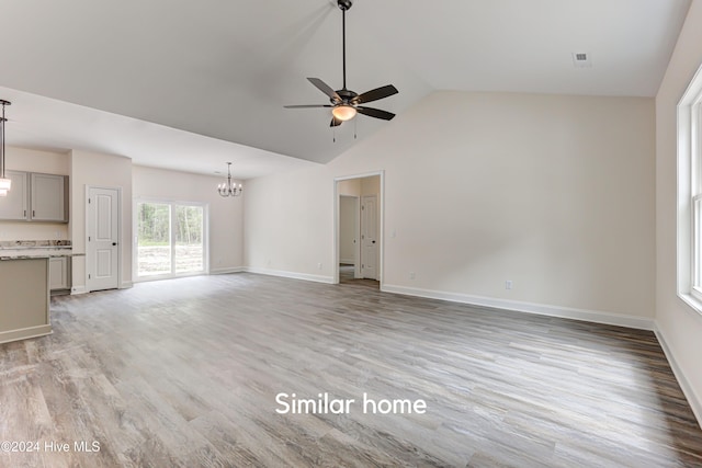 unfurnished living room featuring ceiling fan with notable chandelier, light hardwood / wood-style flooring, and lofted ceiling