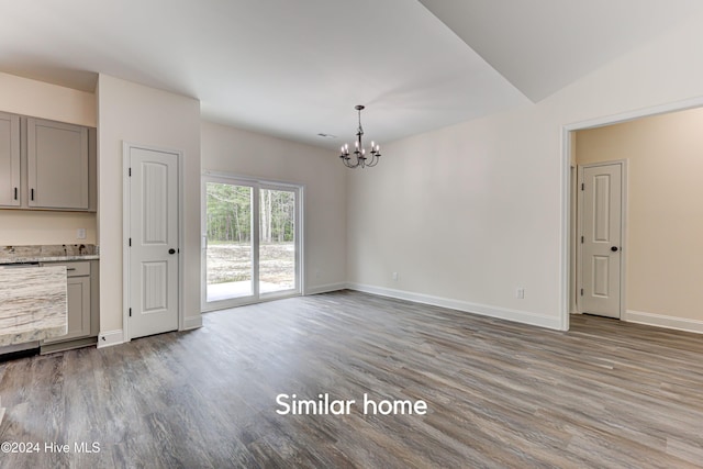 unfurnished dining area featuring a chandelier, hardwood / wood-style flooring, and lofted ceiling