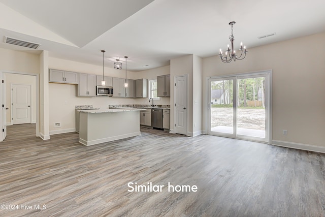 kitchen with pendant lighting, gray cabinets, light hardwood / wood-style floors, appliances with stainless steel finishes, and a kitchen island