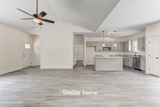 kitchen with gray cabinetry, stainless steel appliances, vaulted ceiling, light hardwood / wood-style floors, and a kitchen island