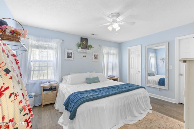 bedroom featuring a textured ceiling, light hardwood / wood-style floors, multiple windows, and ceiling fan