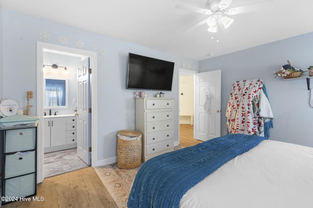 bedroom featuring light hardwood / wood-style floors, ensuite bath, ceiling fan, and sink