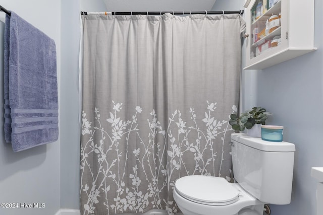 bathroom featuring toilet and curtained shower