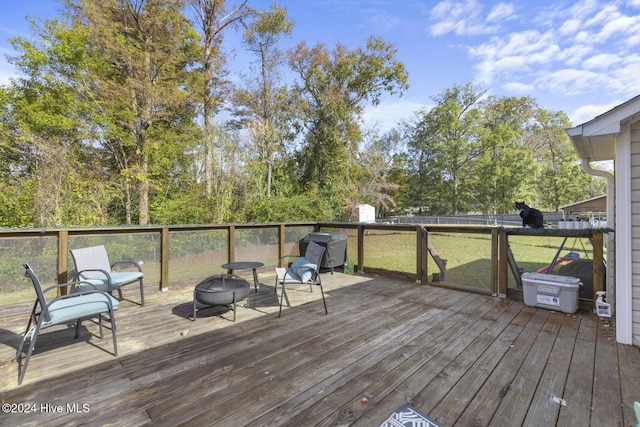 wooden deck featuring a yard and a fire pit