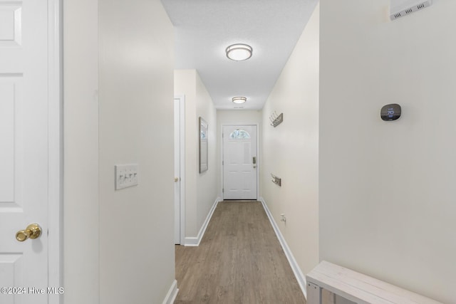 hall featuring a textured ceiling and light hardwood / wood-style floors