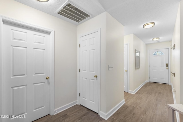 hallway with light wood-type flooring and a textured ceiling